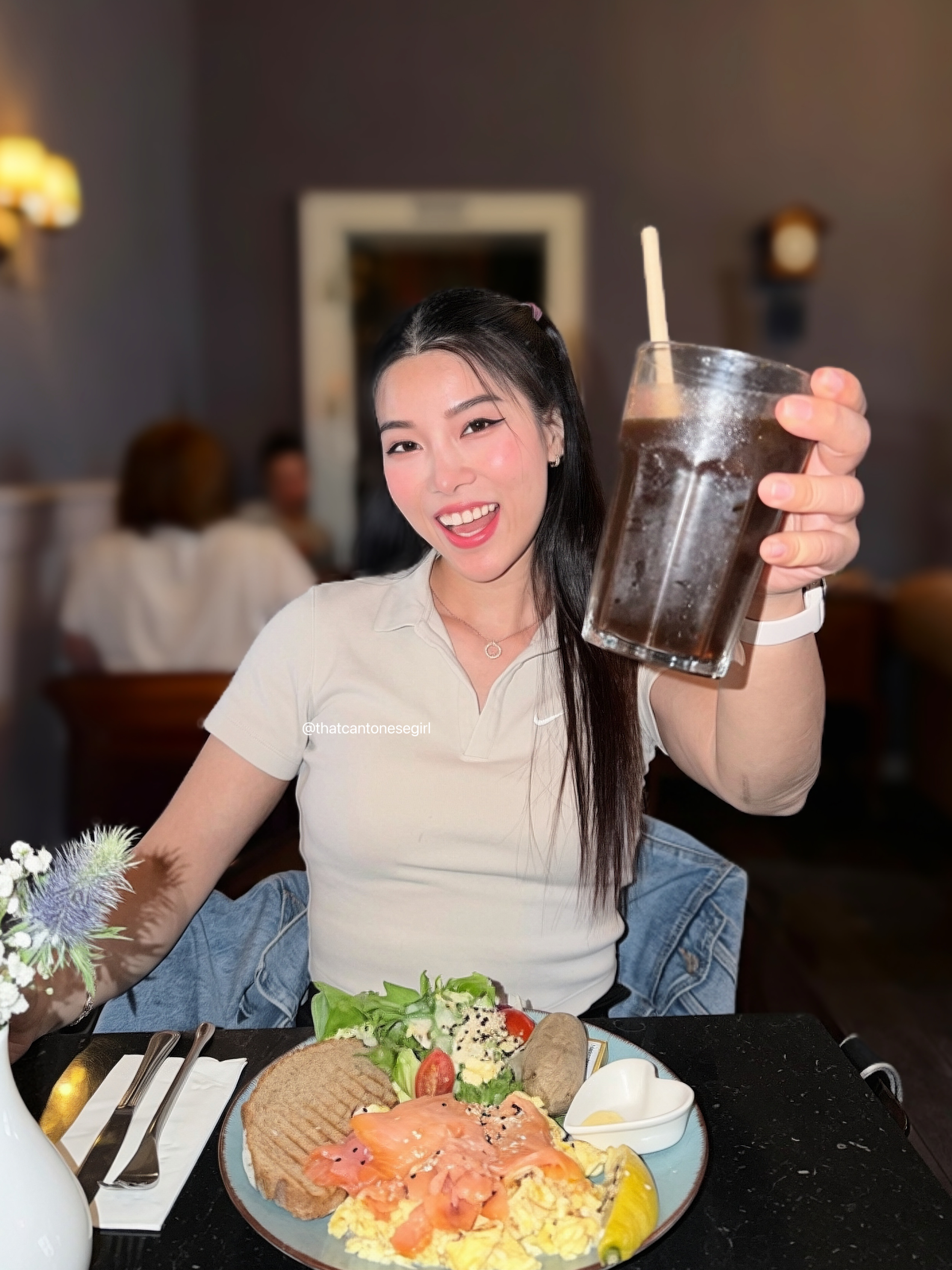 Emely raising an iced drink at a brunch table